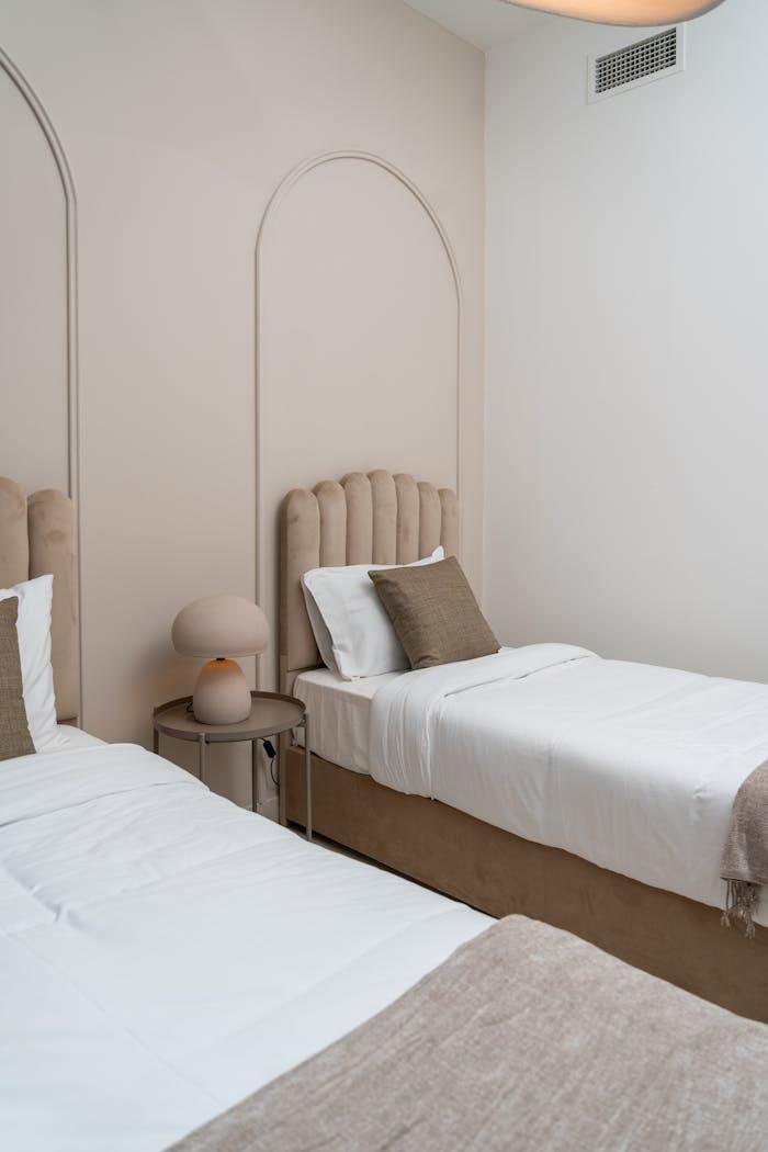 A stylish twin bed setup in a Dubai hotel room featuring neutral tones and modern elegance.