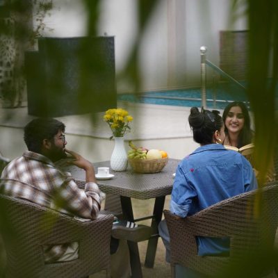 Relaxing outdoor gathering by the poolside with friends, featuring lush greenery, comfortable seating, and refreshing beverages at Palm Leisure for a luxurious experience.