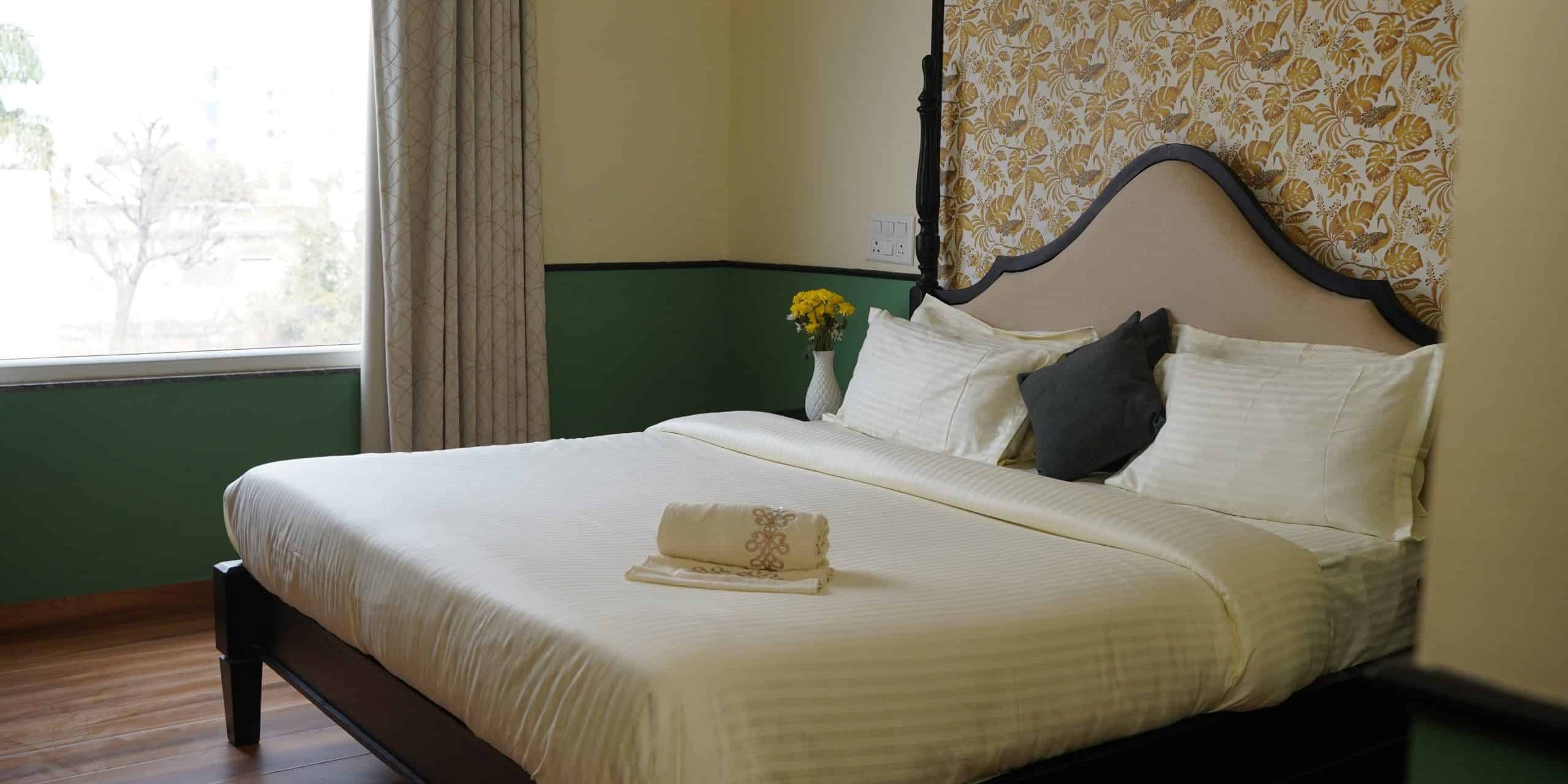 Spacious hotel bedroom with a neatly made bed, decorative headboard, and fresh linens, offering a relaxing atmosphere in a luxurious Palm Leisure resort.