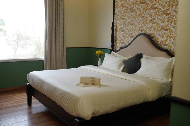 Spacious hotel bedroom with a neatly made bed, decorative headboard, and fresh linens, offering a relaxing atmosphere in a luxurious Palm Leisure resort.