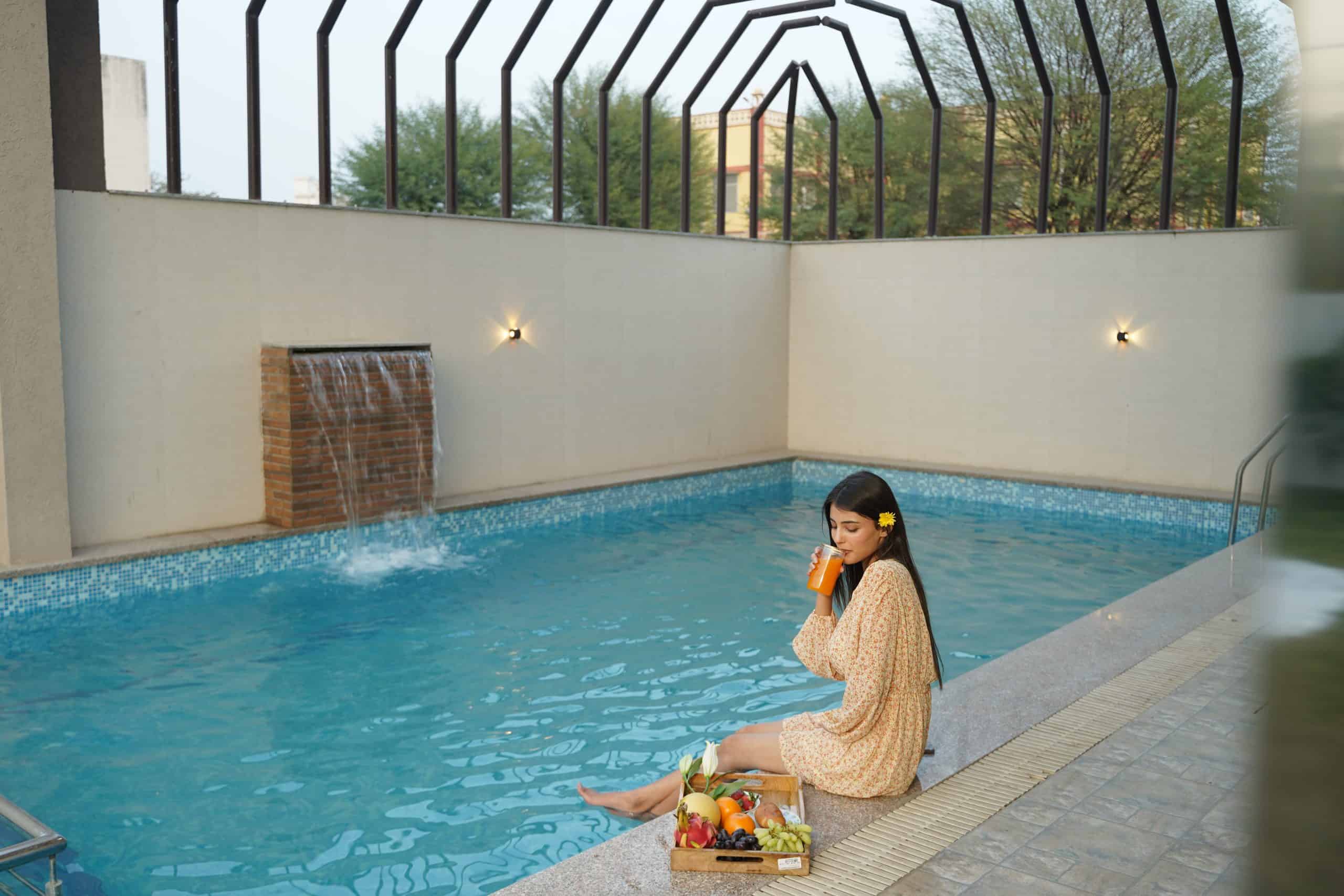 Relaxing woman enjoying a refreshing orange drink by a private pool at Palm Leisure resort, emphasizing luxury poolside experience and tropical amenities for ultimate relaxation.